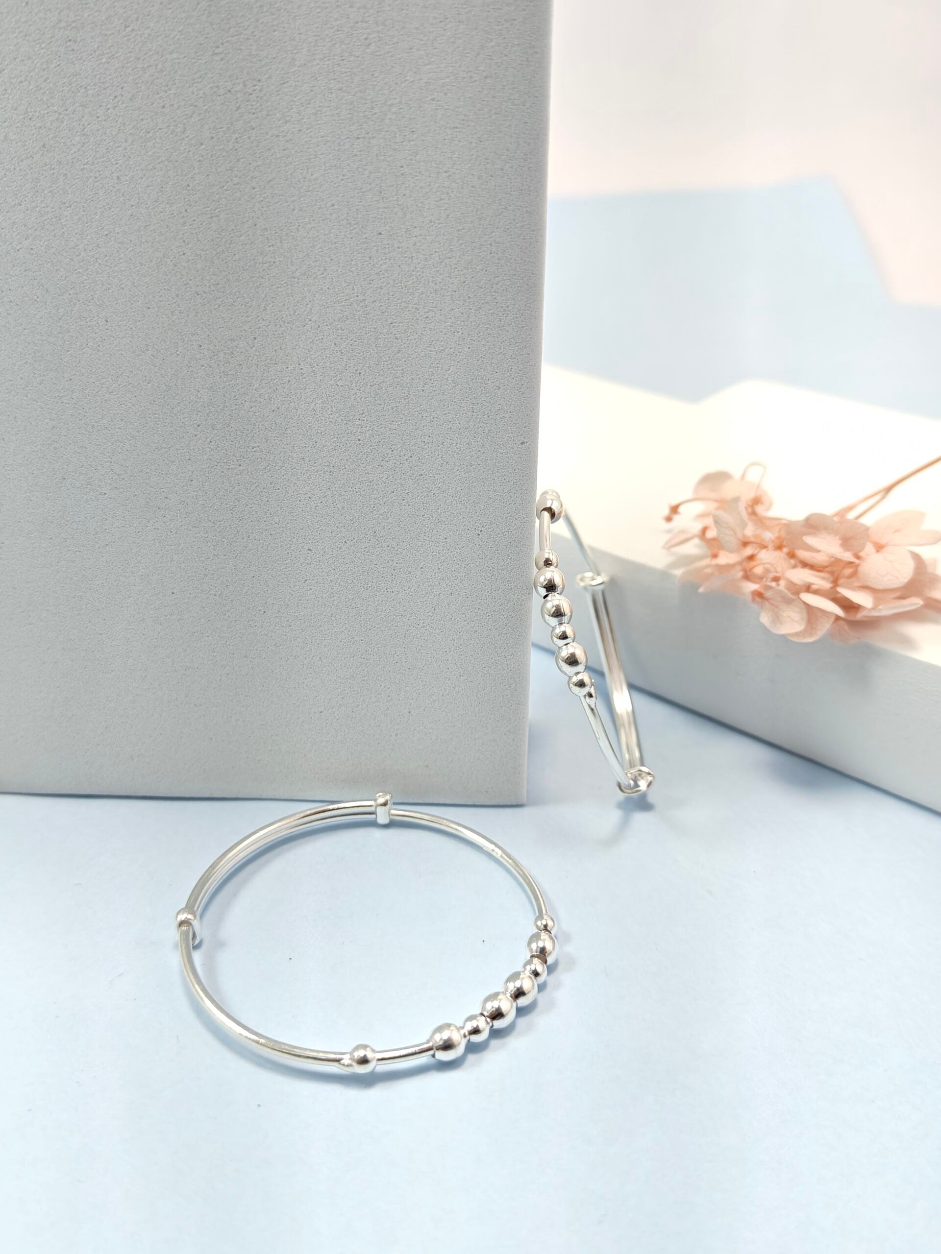 Silver bracelet with beaded design on a light blue surface